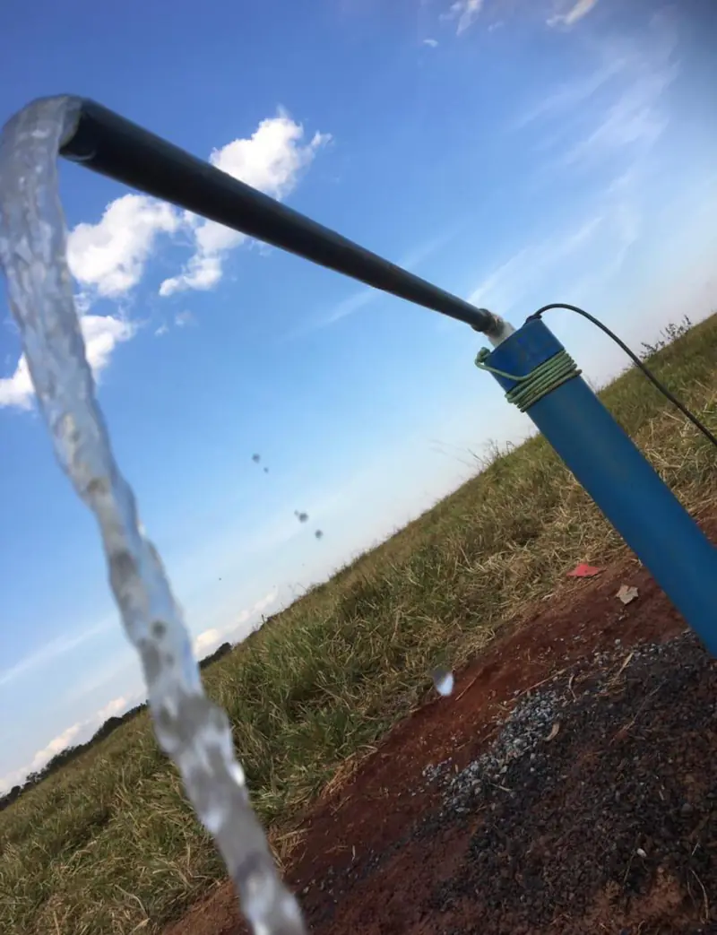 Água saindo da tubulação de um poço em uma propriedade rural
