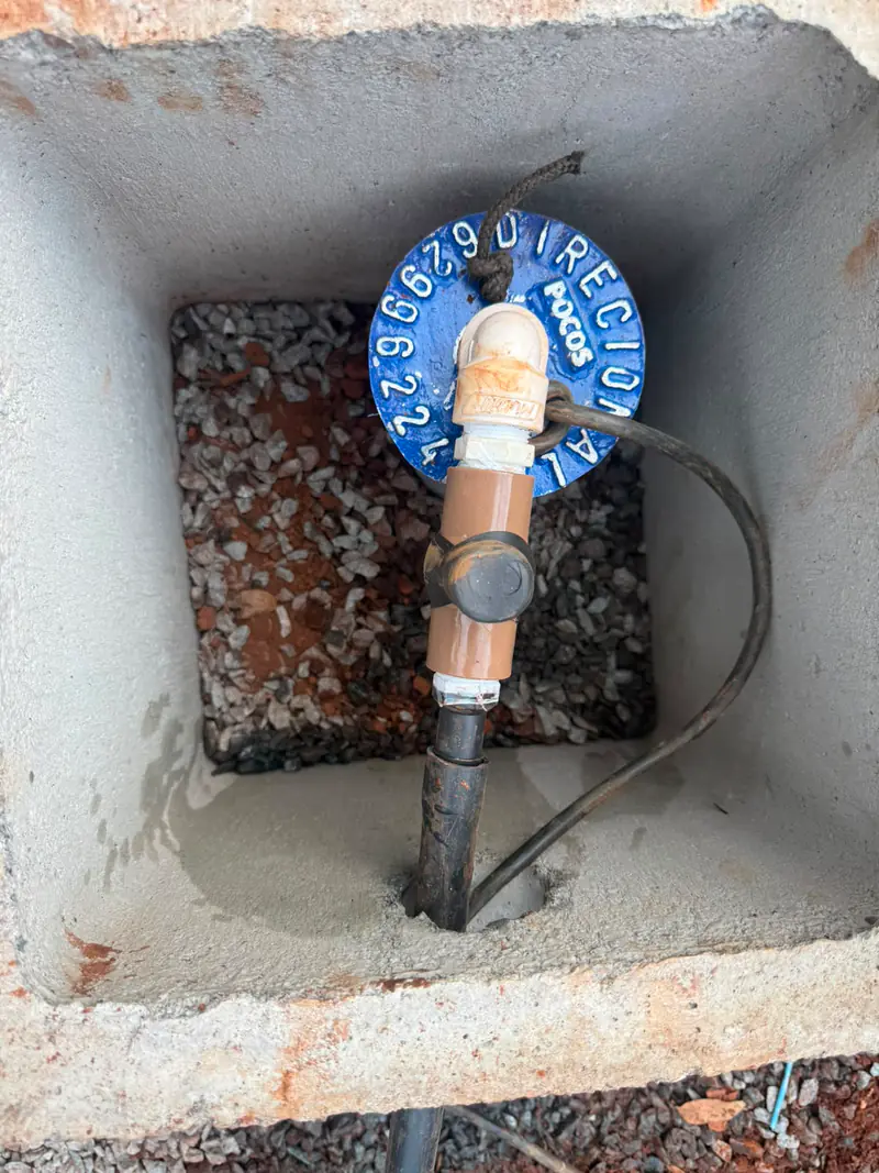 Tampa azul com o nome Direcional dentro de uma caixa de concreto, com tubulação e cabos.